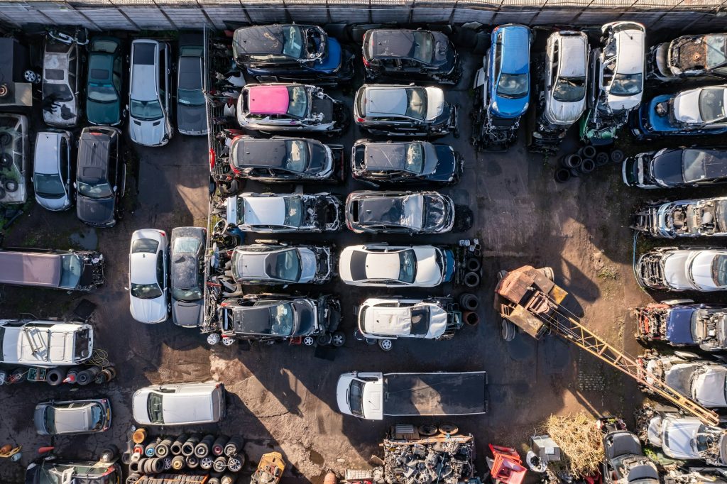 Full frame aerial view directly above scrap yard and rows of scrap metal cars